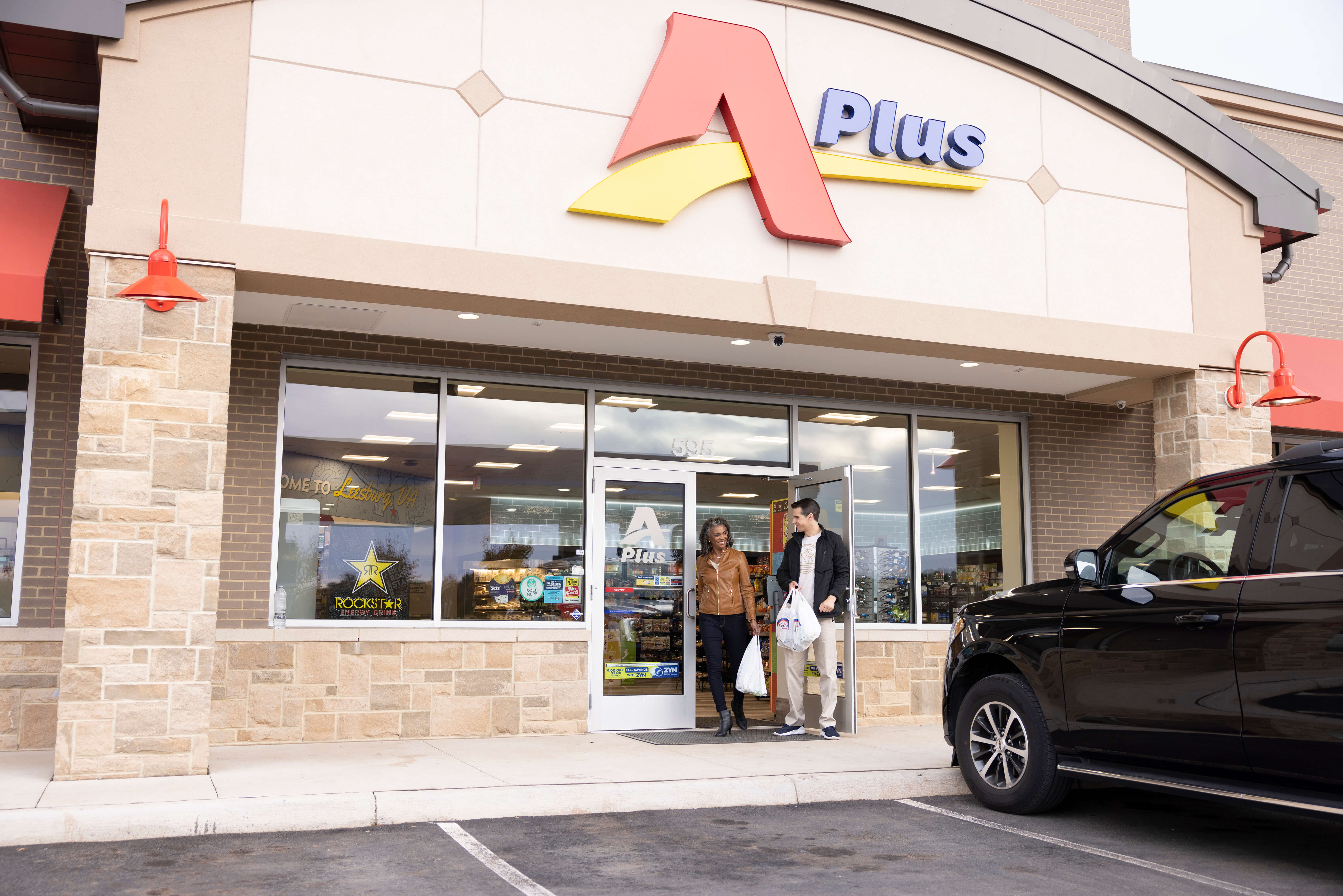 A man and a women exiting an APlus convenience store