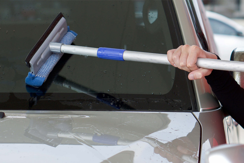 Gas station worker cleaning the car windshield with window squeegee